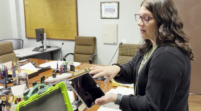 Bourbon County Clerk Susan Walker demonstrates a KNOWiNK Poll Pad — the electronic check-in tablet used at polling places — at the Bourbon County Clerk's Office on May 22, 2026.
