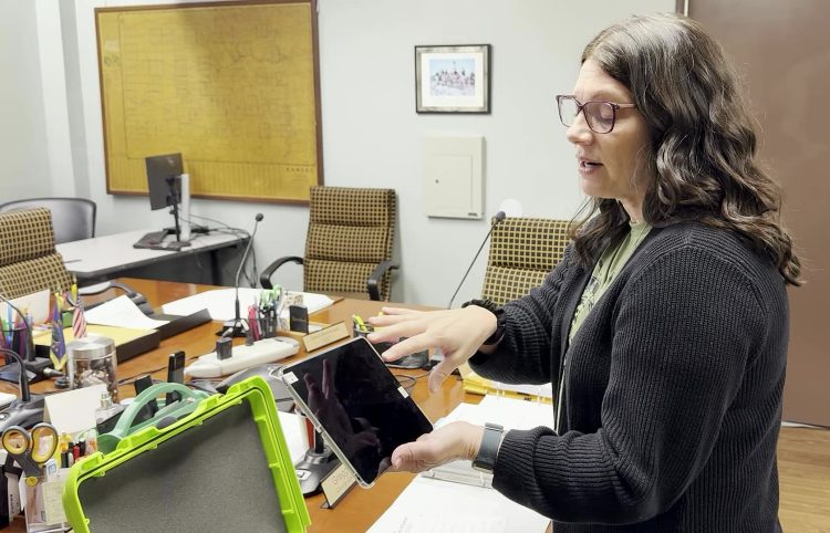 Bourbon County Clerk Susan Walker demonstrates a KNOWiNK Poll Pad — the electronic check-in tablet used at polling places — at the Bourbon County Clerk's Office on May 22, 2026.